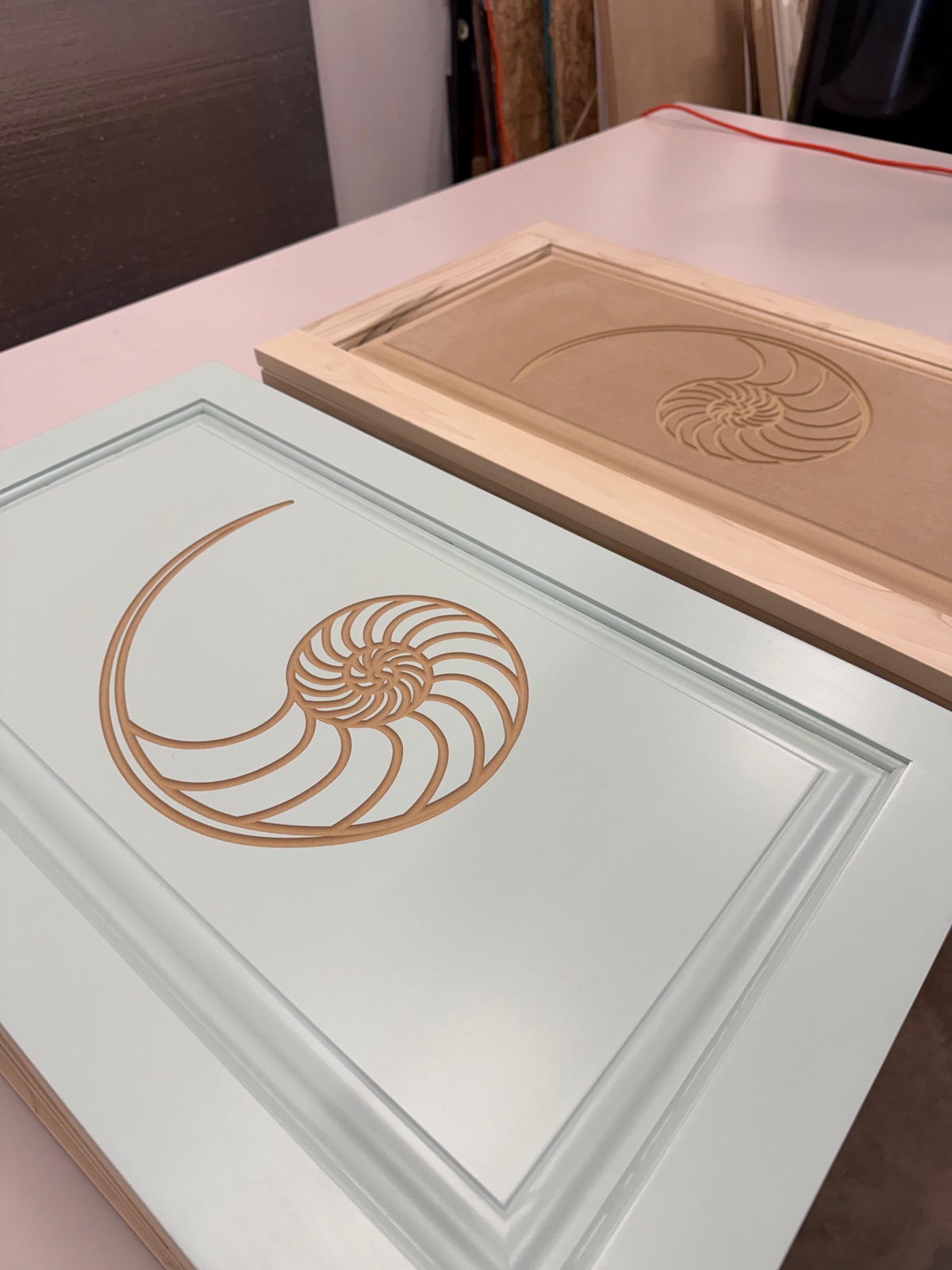 Detail of the mirrored nautilus engraving on the client's mint finish sample, with a raw engraved panel behind it