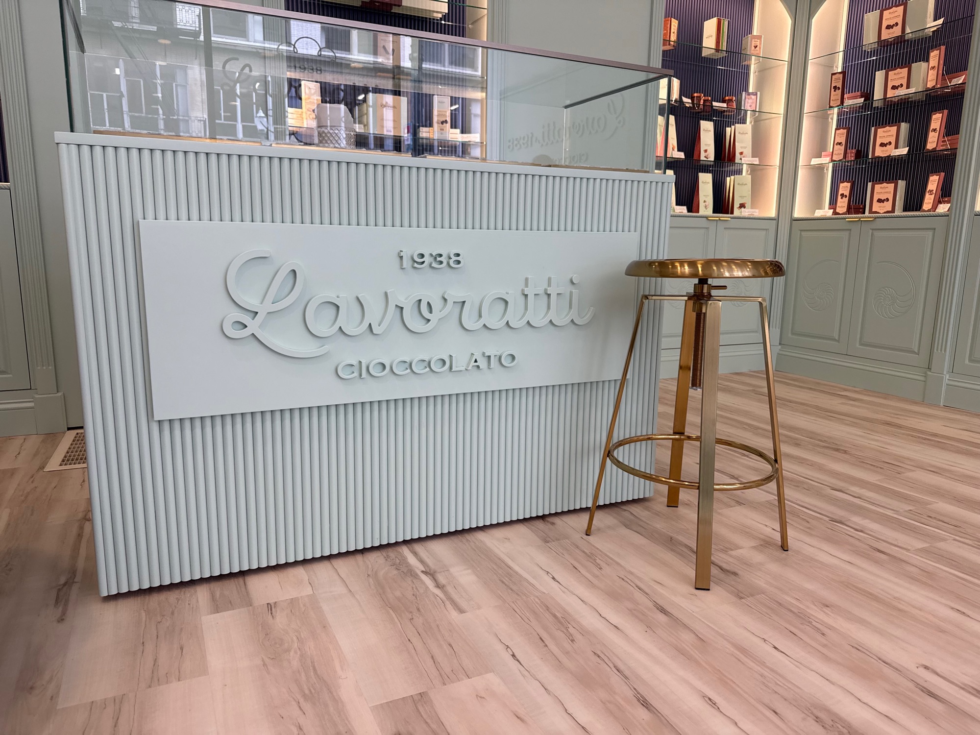 Lavoratti Cioccolato showroom counter with dimensional CNC-routed script lettering on a fluted mint green front