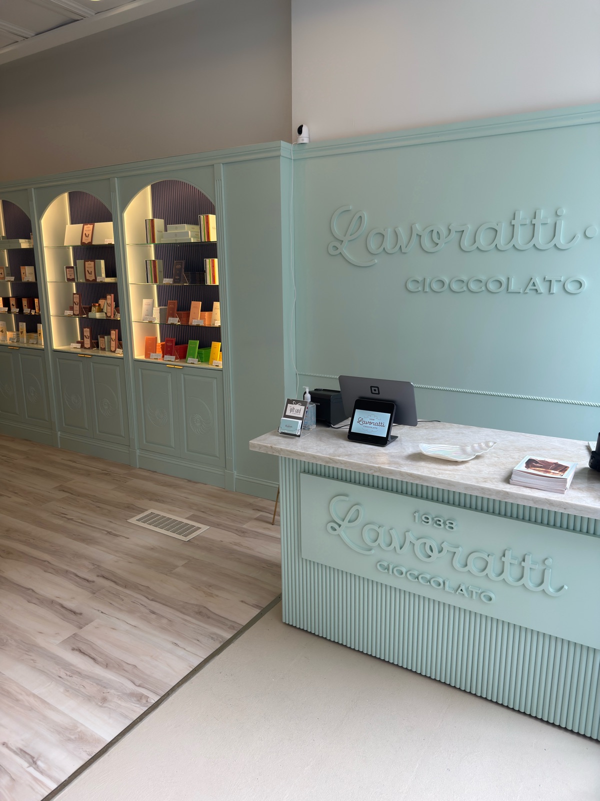 Wide view of the finished Lavoratti Cioccolato showroom, engraved cabinet doors on the left and the dimensional lettering at the counter