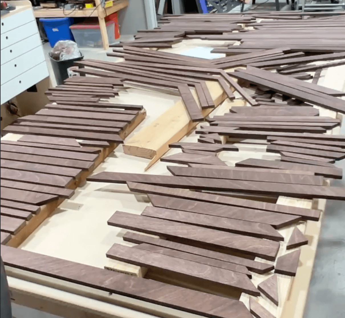 Top-layer pieces stained in mahogany and numbered, queued for assembly